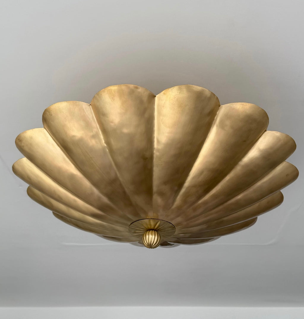 A vintage-style gold ceiling light fixture with a scalloped, shell-like metallic design, mounted on a plain light gray ceiling.
