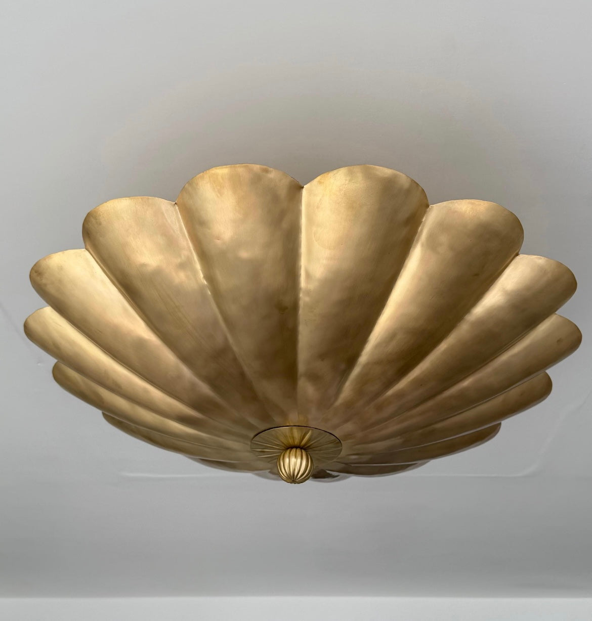 A vintage-style gold ceiling light fixture with a scalloped, shell-like metallic design, mounted on a plain light gray ceiling.