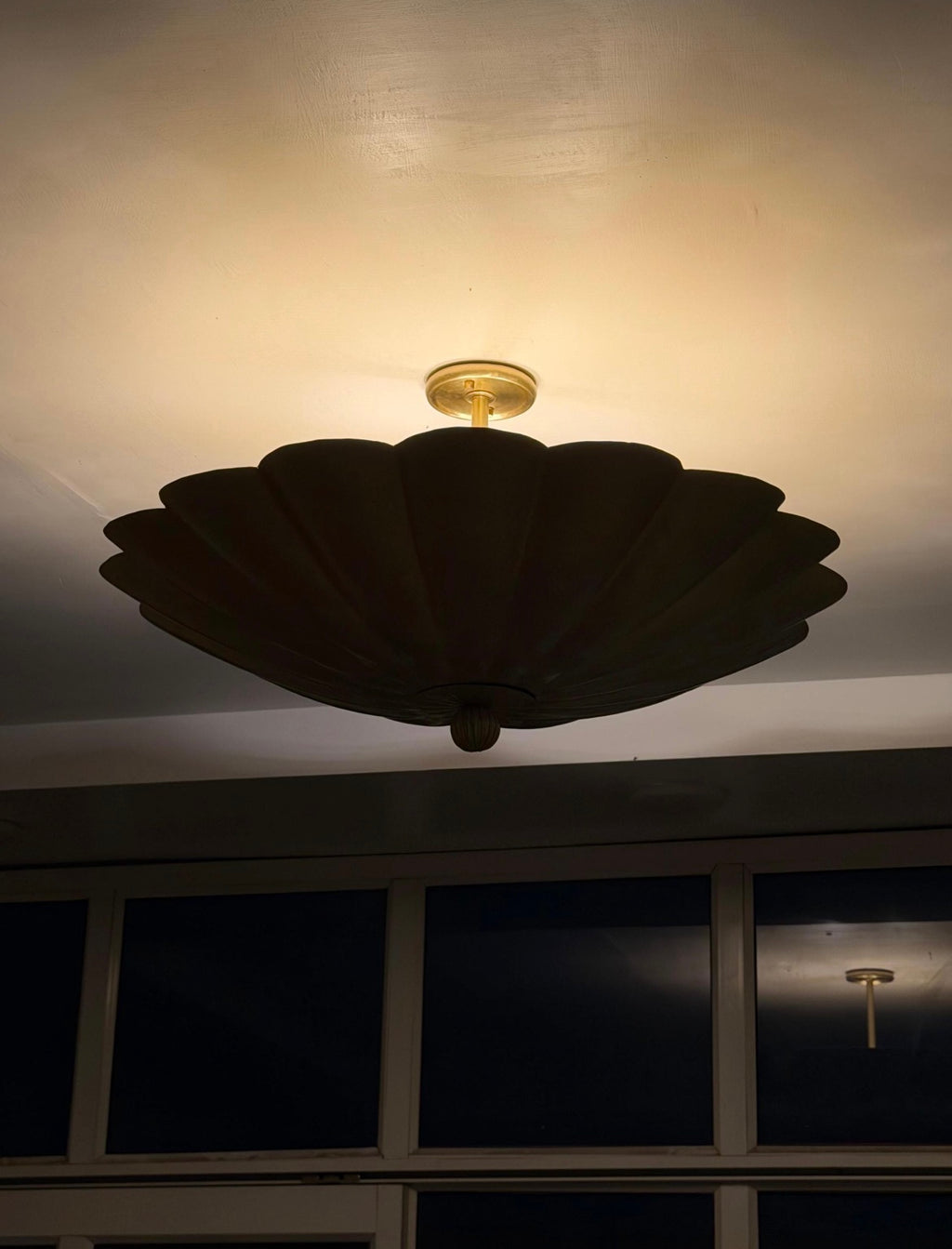 Brass scalloped ceiling light illuminated