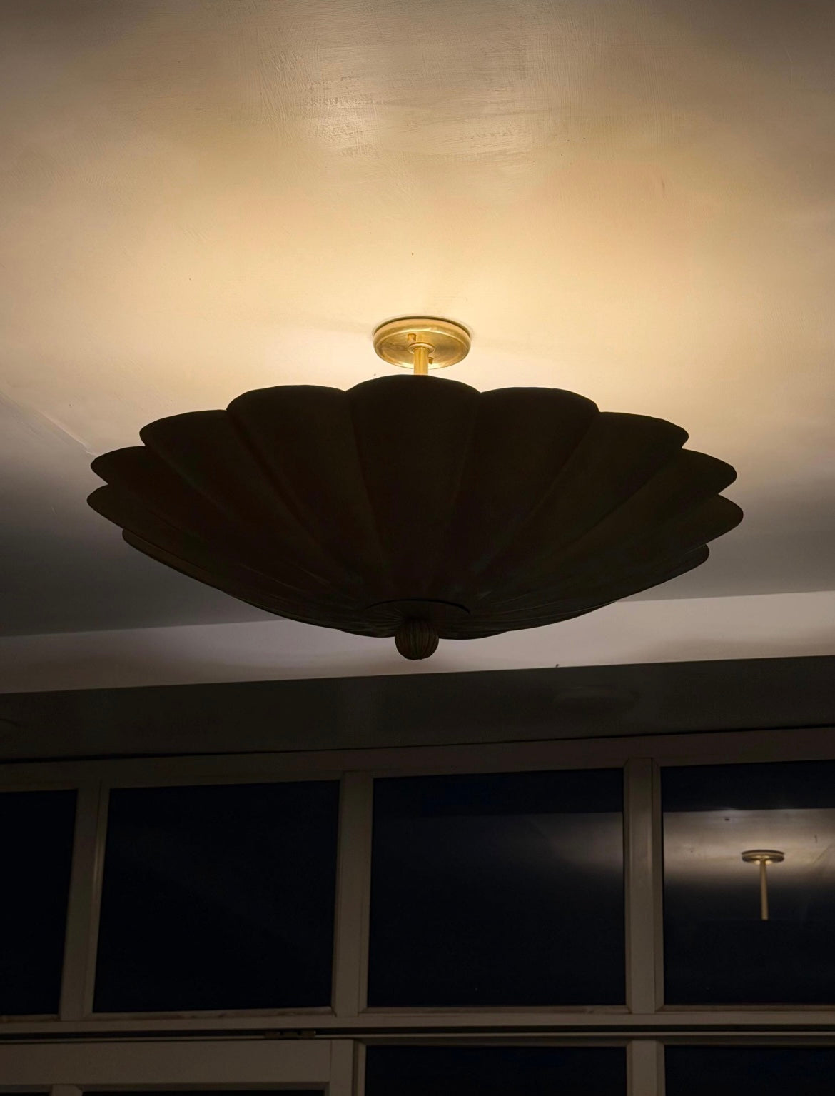 Brass scalloped ceiling light illuminated