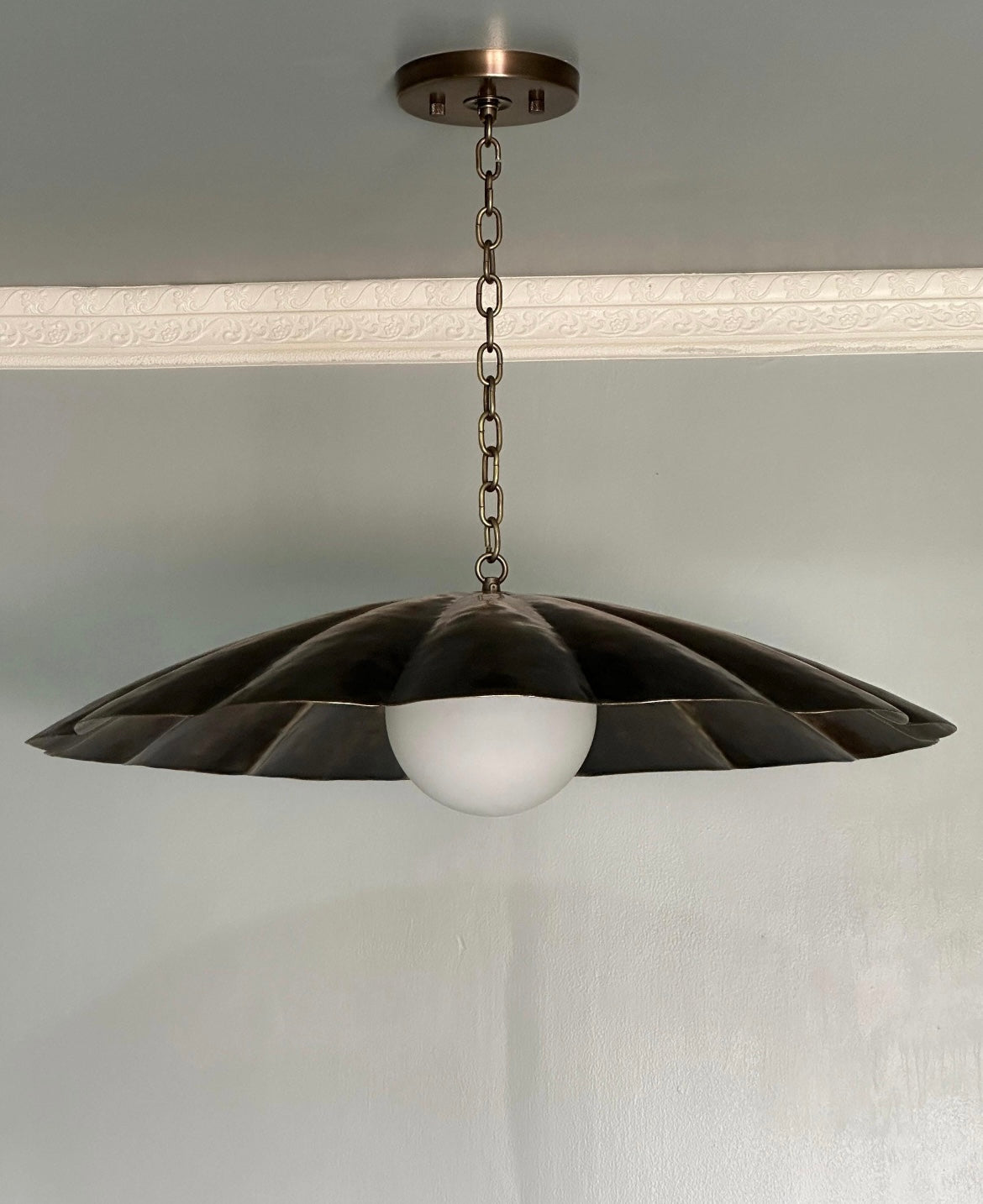 Handcrafted antique brass scalloped flower pendant light with chain detail.