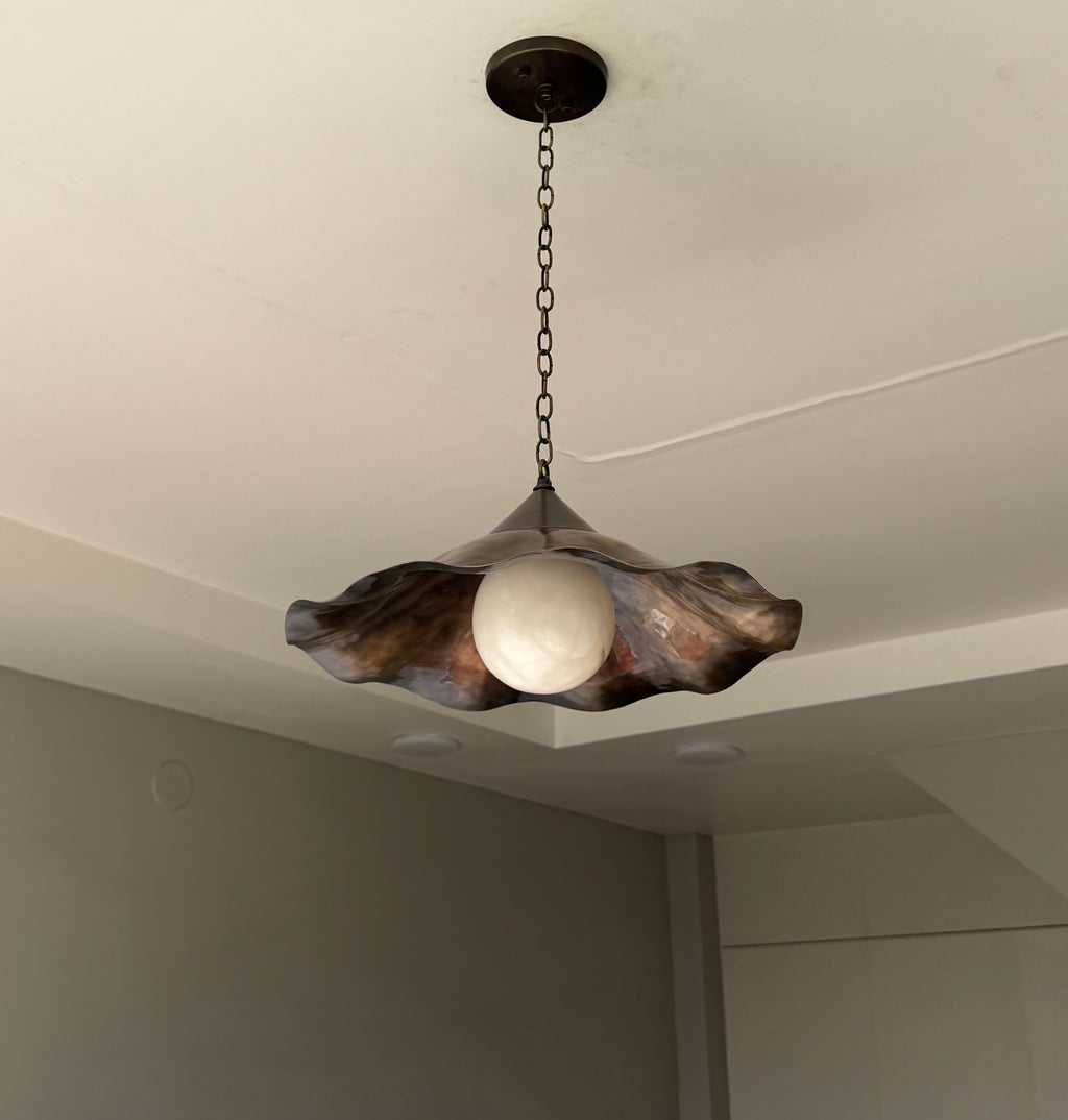 Scalloped brass pendant light glowing warm light in corner