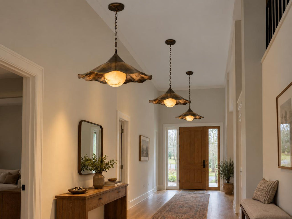 Scalloped brass pendant light glowing warm light in entryway