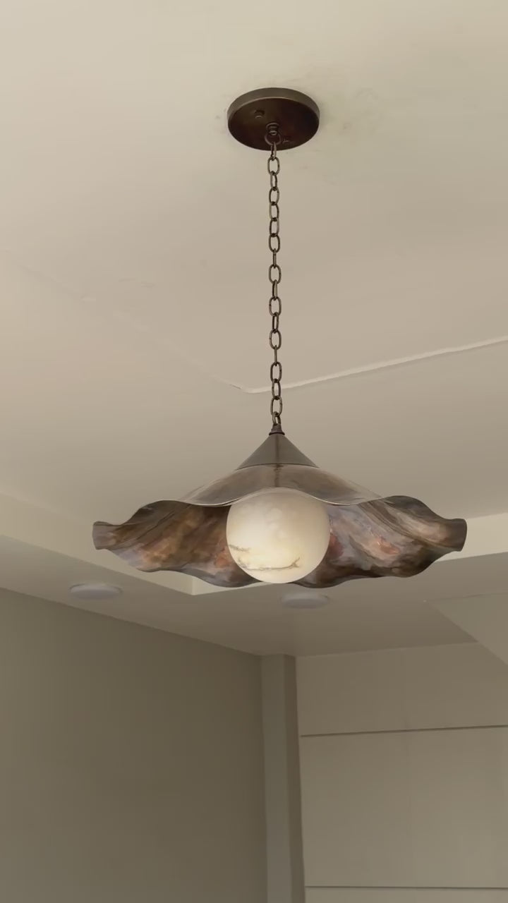 Vintage brass wavy pendant light hanging from ceiling